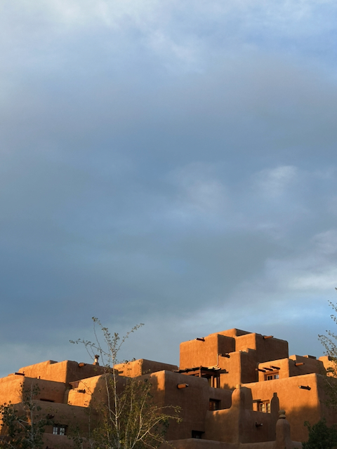 Adobe buildings glowing orange beneath dark evening clouds in Santa Fe