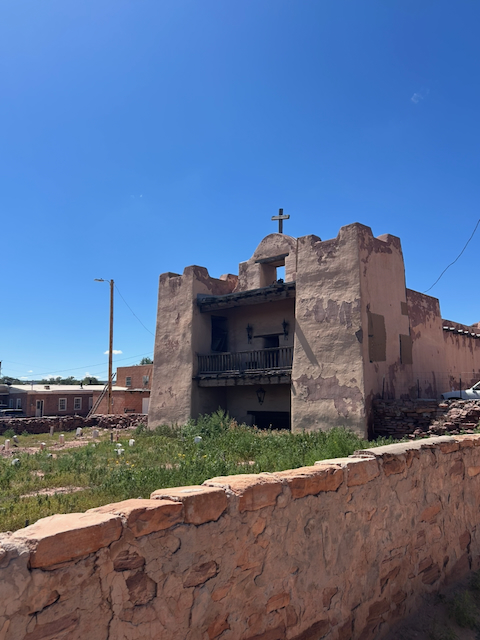 An old adobe mission church beneath an intensely blue sky in Zuni Pueblo